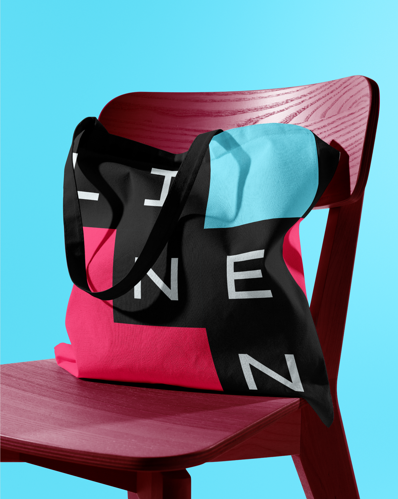 Linen brand visual — black tote bag with logo on pink chair